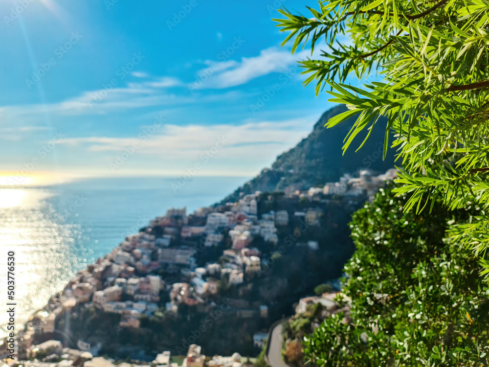 Panoramic view on colorful houses of coastal town Positano, Amalfi Coast, Italy, Campania, Europe. Branch of tree in foreground. Vacation at coastline at Tyrrhenian, Mediterranean Sea. Path of Gods