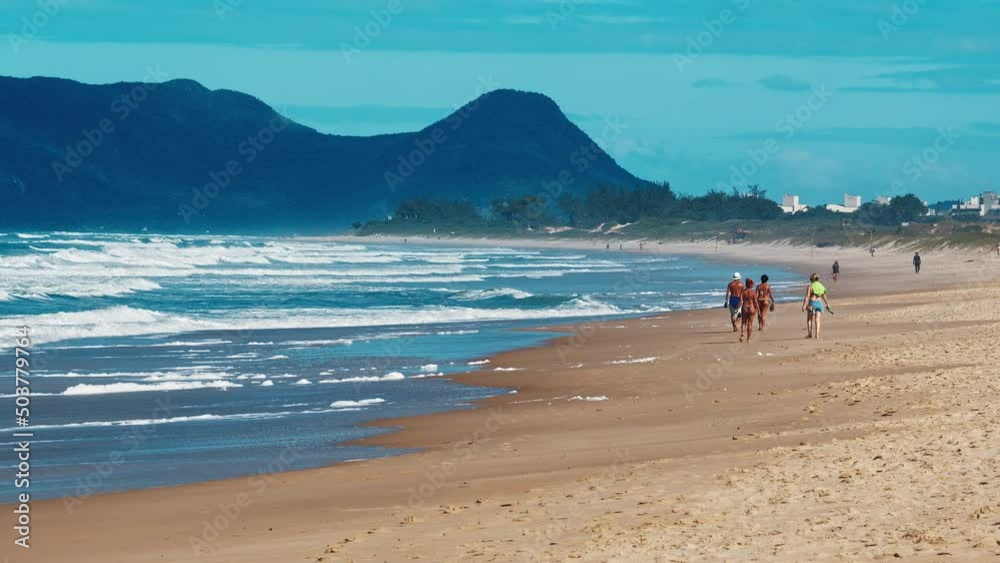 Brazilian coastline. People relax on the sandy beach with rolling waves of Atlantic Ocean, town of Campeche, Brazil Brazilian coastline. People relax on the sandy beach with rolling waves of Atlantic Ocean, town of Campeche, Brazil