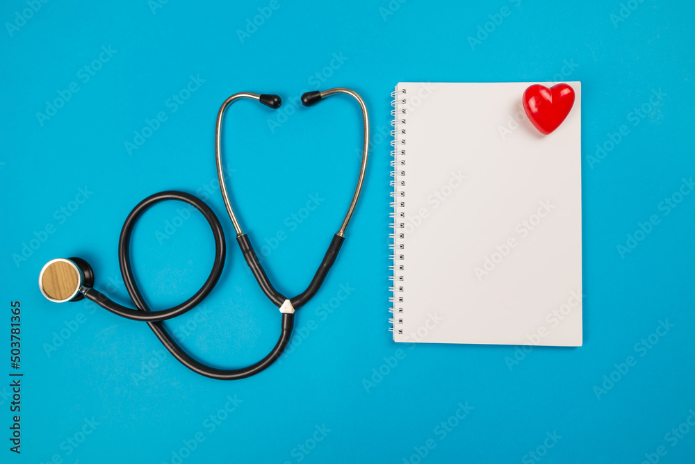 Blank notepad ,stethoscope and red heart on blue. View from above. Place for text. Blank notepad ,stethoscope and red heart on blue. View from above. Place for text.