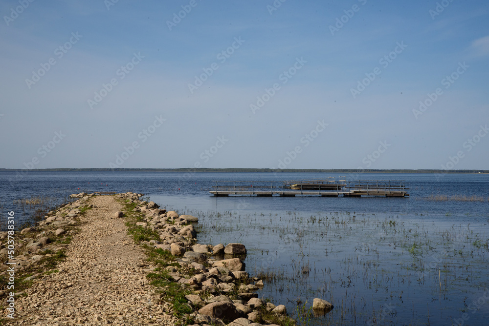 beautiful view of the lake on a sunny day with a rocky pier in spring