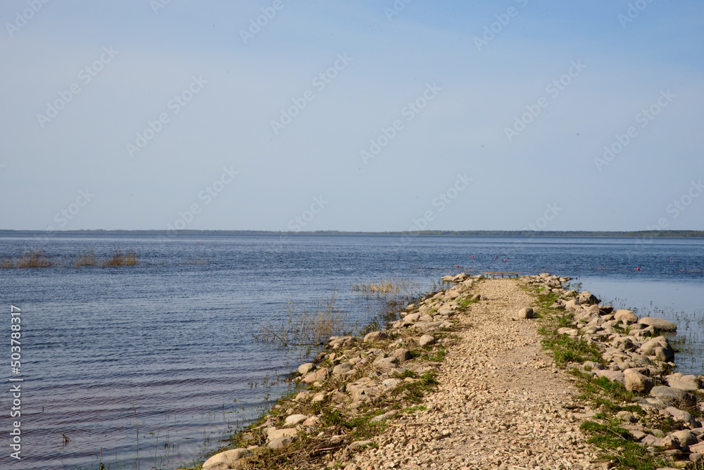 beautiful view of the lake on a sunny day with a rocky pier in spring