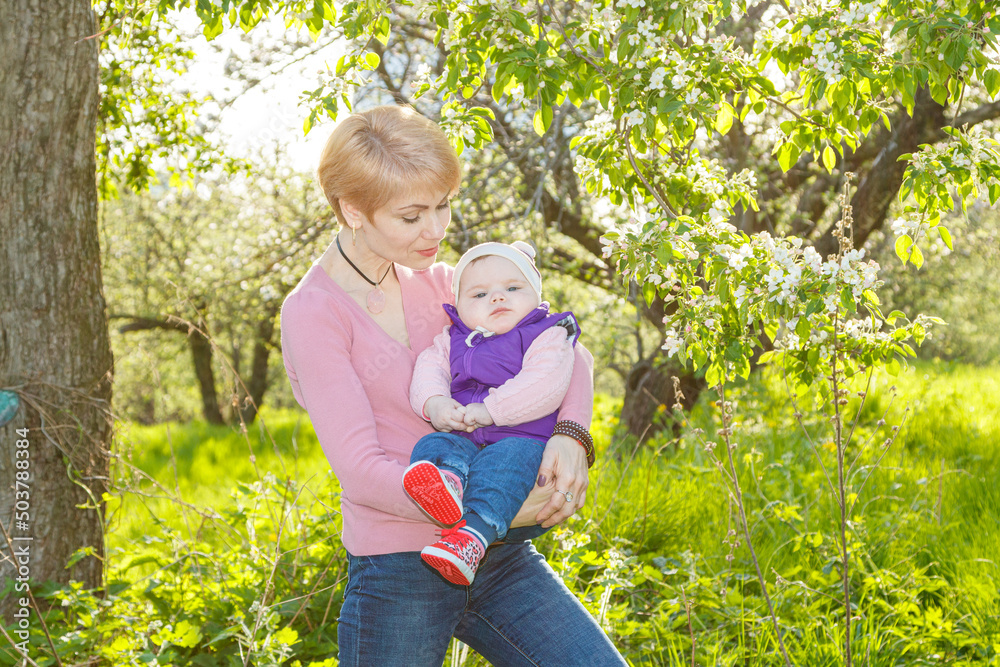 Fototapeta premium Beautiful girl in the arms of a child girl in a blooming park