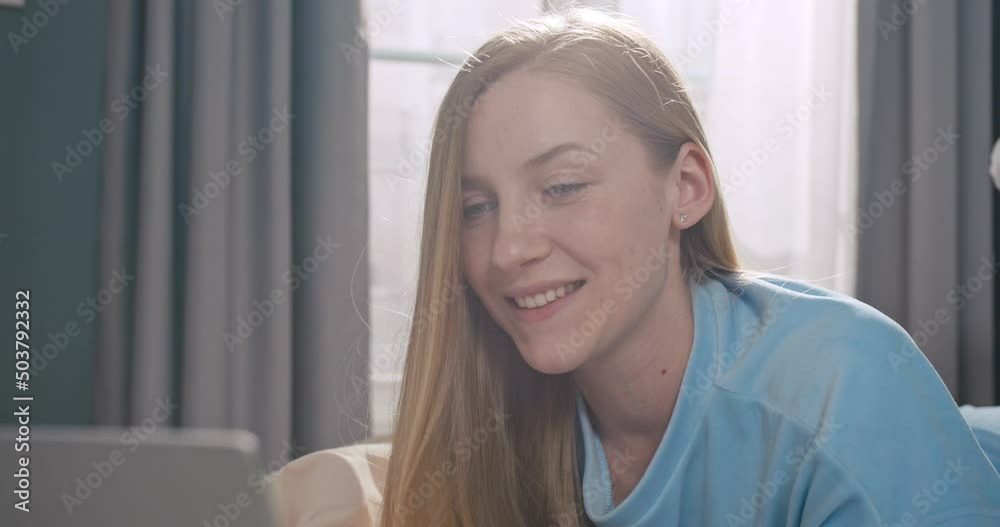 Portrait of young caucasian woman styding in her bedroom. Pretty female lying on bed and using laptop notebook to work. Portrait of young caucasian woman styding in her bedroom. Pretty female lying on bed and using laptop notebook to work.