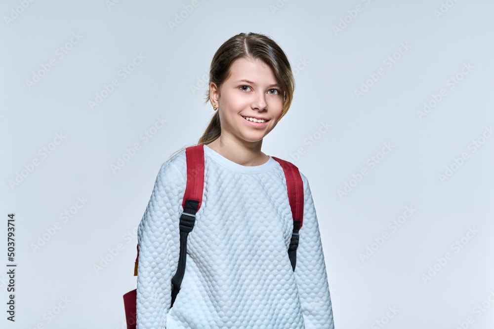 Portrait of schoolgirl 11, 12 years old with backpack, girl looking at camera on light studio background Portrait of schoolgirl 11, 12 years old with backpack, girl looking at camera on light studio background