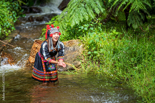 Fototapeta Naklejka Na Ścianę i Meble -  A young hill tribe woman is playing in the water on the waterfall. Hmong hill tribe clothes.