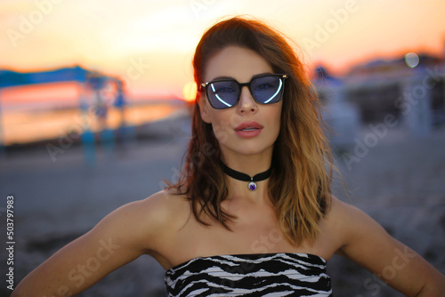 fashionable girl on the background of the ocean in glasses at sunset