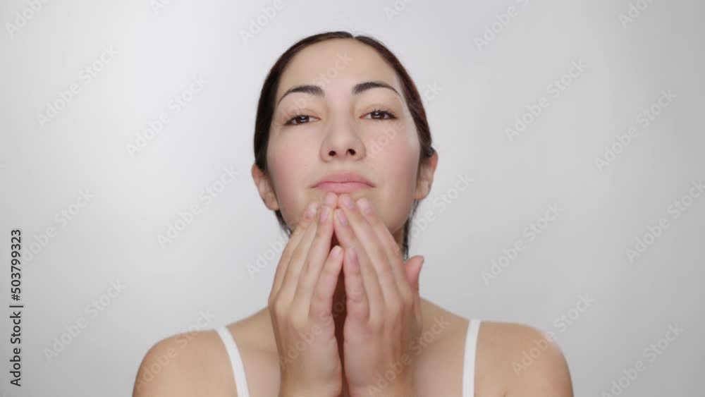 Beautiful brunette woman gently applies primer to face with fingers in studio Beautiful brunette woman gently applies primer to face with fingers in studio