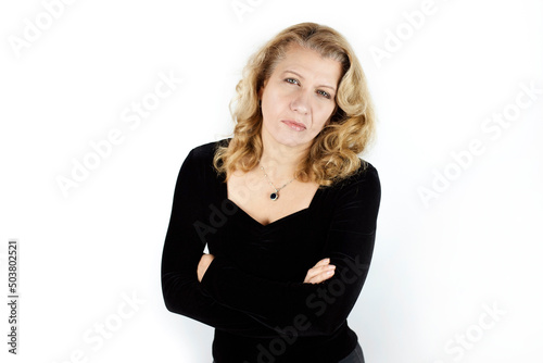 Woman on a light background looks suspiciously at the camera, with disbelief. The woman has a pretty face but sad and with feelings of doubt and suspicion
