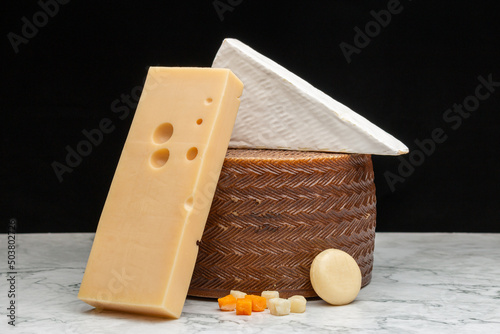 Closeup image of a white Akawi, Cheddar and Queso Blanco cheese and a small round cheese photo