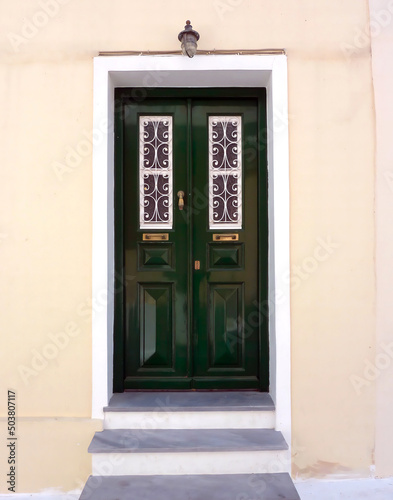 An elegant classic house entrance with green painted door, Chora town, Andros island, Greece.