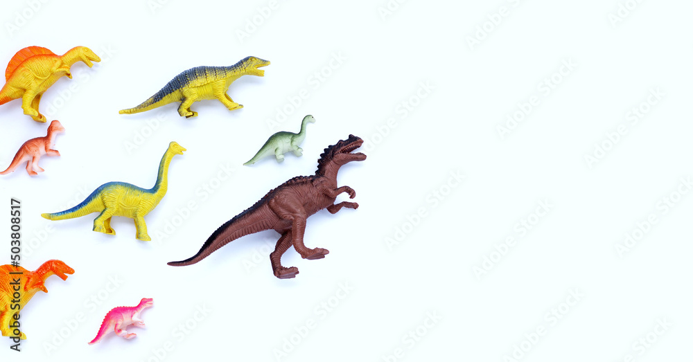 Fototapeta premium Plastic dinosaur toys on white background. Top view