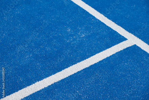 white lines on a blue paddle tennis court with artificial grass. racket sports concept