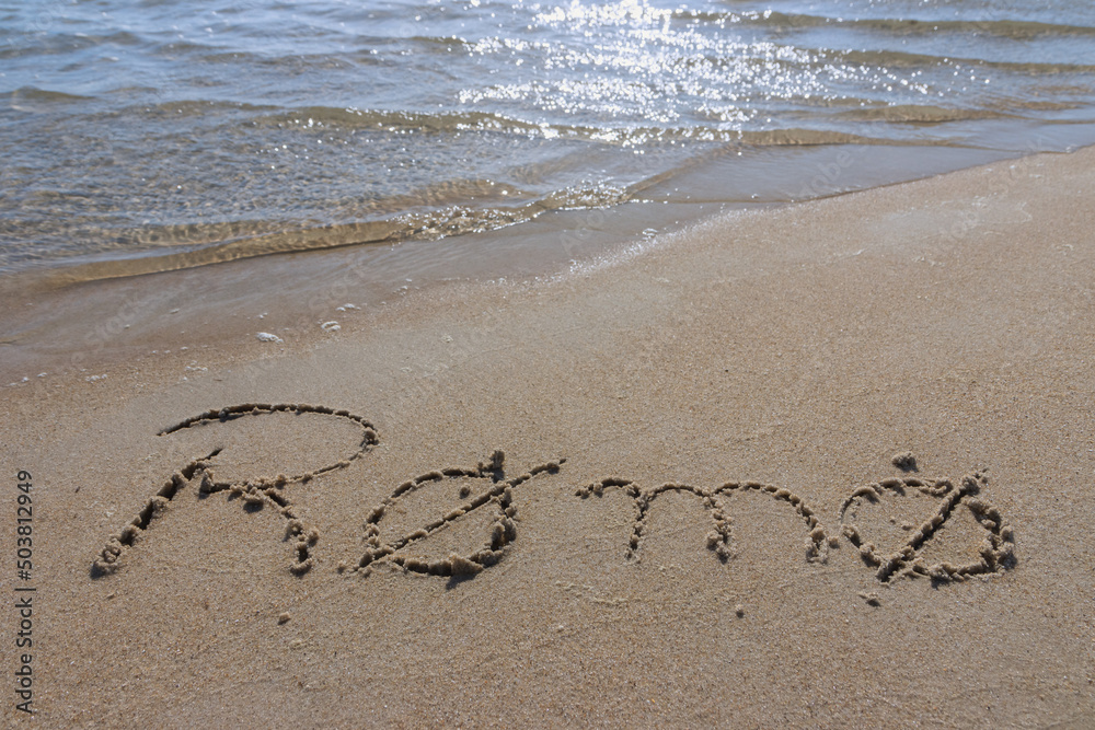 Fototapeta premium Rømø written in the sand at the beach.