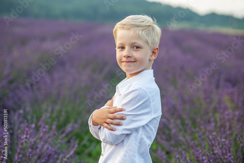 Fototapeta Naklejka Na Ścianę i Meble -  Blond boy of school age. Child portrait in purple lavender field in summer.