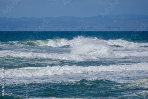 Crashing surf on a beautiful Pacific Ocean Beach beneath the bright blue sky