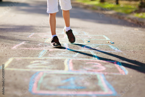 Kids play hopscotch in summer park. Outdoor game. photo