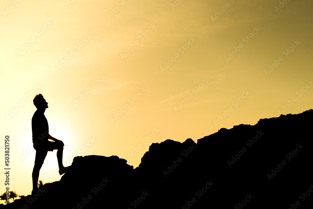 silhouette of a man climbing a mountain, triumph and personal achievement, concept of freedom