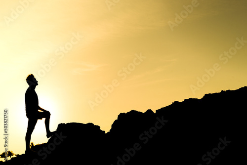 silhouette of a man climbing a mountain, triumph and personal achievement, concept of freedom