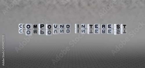 compound interest word or concept represented by black and white letter cubes on a grey horizon background stretching to infinity