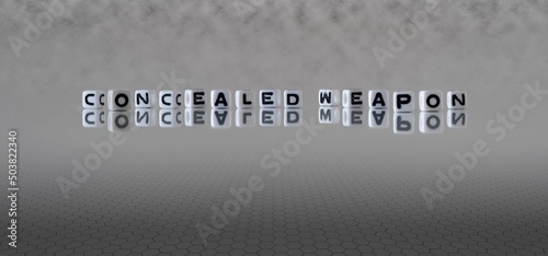concealed weapon word or concept represented by black and white letter cubes on a grey horizon background stretching to infinity