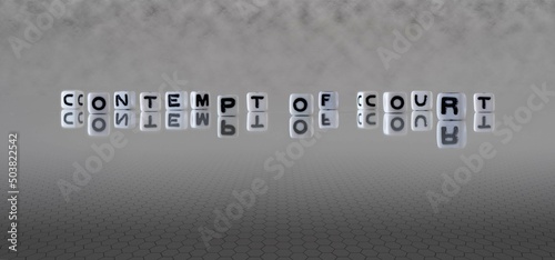 Photos contempt of court word or concept represented by black and white letter cubes on