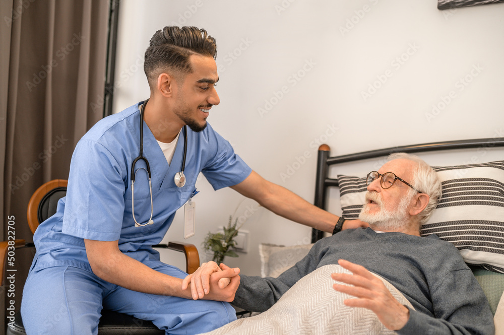 Obraz premium Smiling friendly doctor visiting a bedridden patient