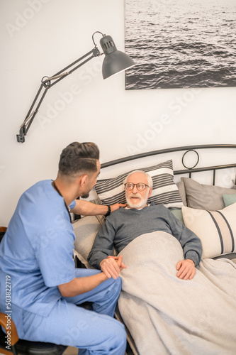 Male physician visiting an ill aged man