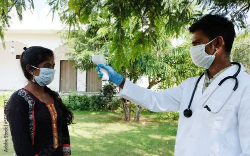 Indian doctor during covid-19 wearing a facemask, check tempreture using a thermometer in India photo