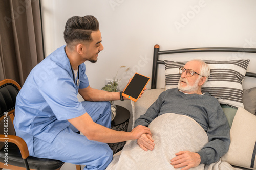 General practitioner examining a bedridden man during the home visit