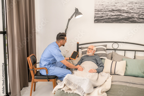 Doctor checking the health condition of a bedridden aged man