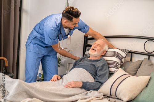 Experienced nurse positioning the patient in bed