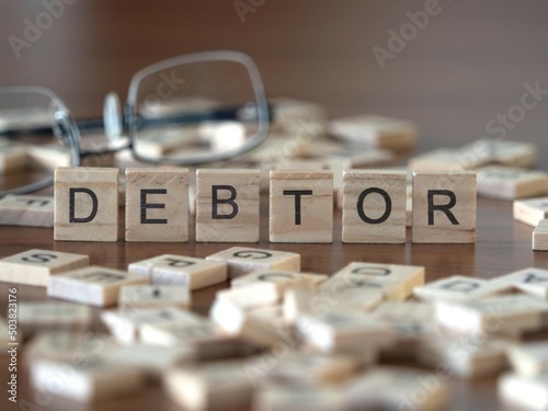 Fotobehang debtor word or concept represented by wooden letter tiles on a wooden table with