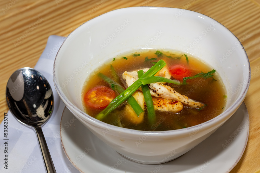 Chicken soup with vegetables in white bowl. Grey stone background. Chicken soup with vegetables in white bowl. Grey stone background.