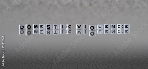 domestic violence word or concept represented by black and white letter cubes on a grey horizon background stretching to infinity