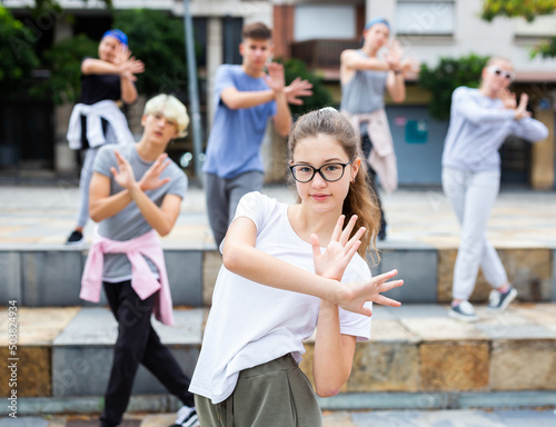 Portrait of emotional girl doing hip hop movements during group class at city street