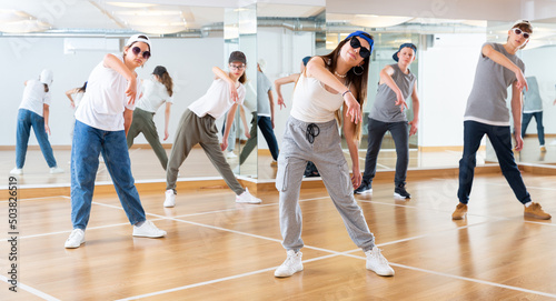 Fototapeta Naklejka Na Ścianę i Meble -  Focused teenage hip hop dancers doing dance workout during group class