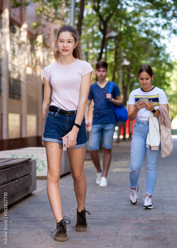 Cute teen girl walking down the street to school