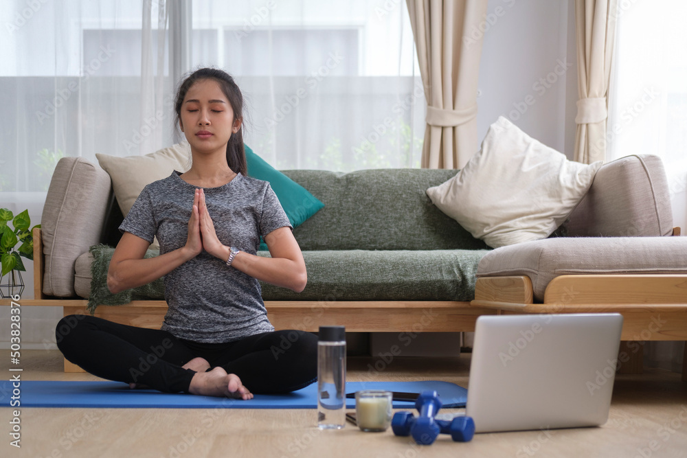 Young woman practicing yoga at home and watching online workout lesson on laptop. Healthy lifestyle concept. Young woman practicing yoga at home and watching online workout lesson on laptop. Healthy lifestyle concept.
