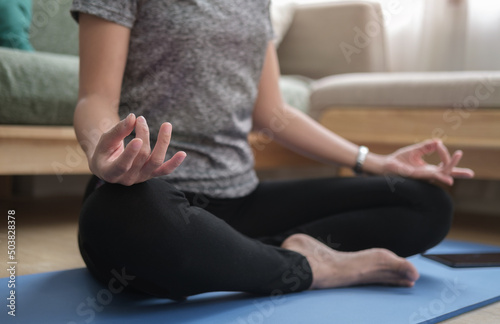Fototapeta Naklejka Na Ścianę i Meble -  Healthy woman practicing yoga at home, sitting in lotus pose to meditation. Healthy lifestyle, meditation concept.