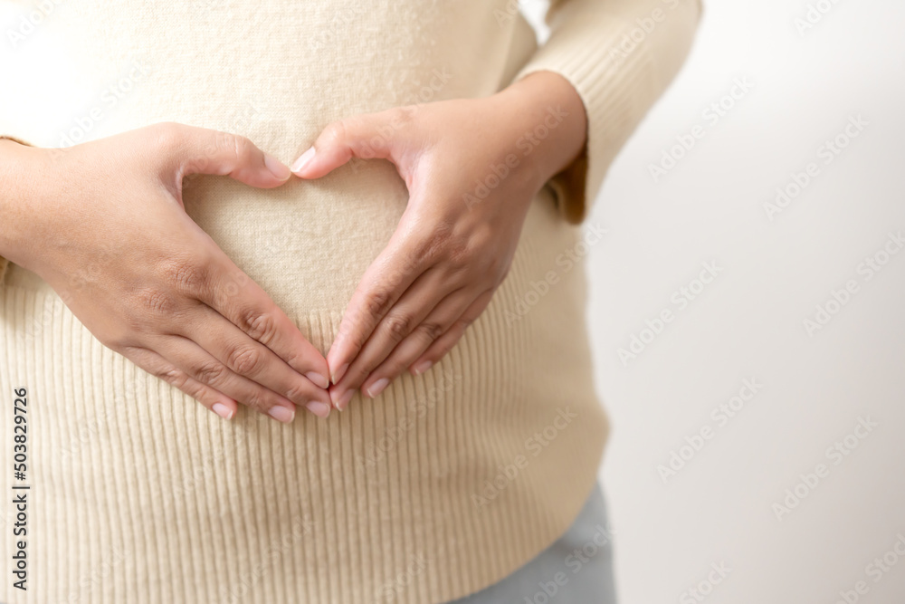 Mother hands doing heart shape at tummy showing concept of pregnancy. Hands into the shape of love to coming newborn baby. Mother hands doing heart shape at tummy showing concept of pregnancy. Hands into the shape of love to coming newborn baby.
