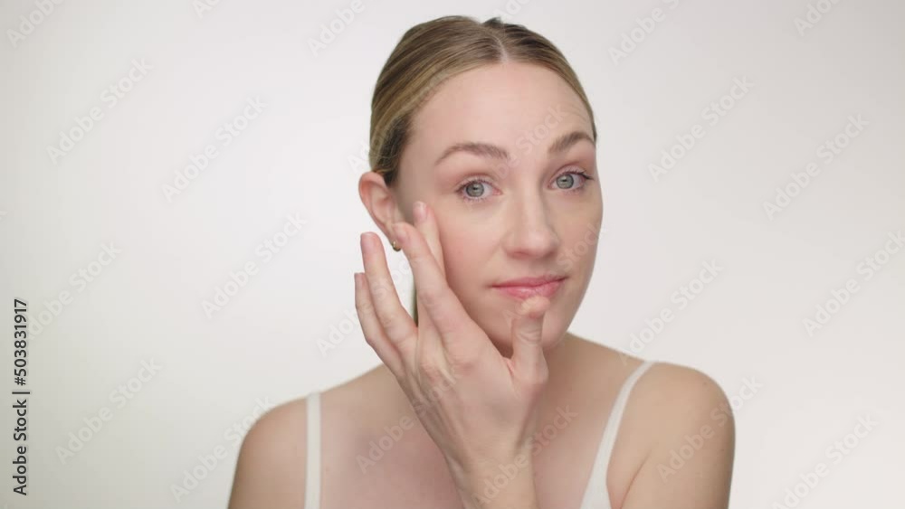 Attractive blonde model applies anti aging cream lotion to fine lines on face Attractive blonde model applies anti aging cream lotion to fine lines on face