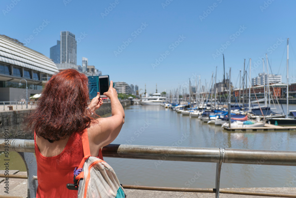 Female tourist taking photos with her phone in Puerto Madero, Buenos Aires