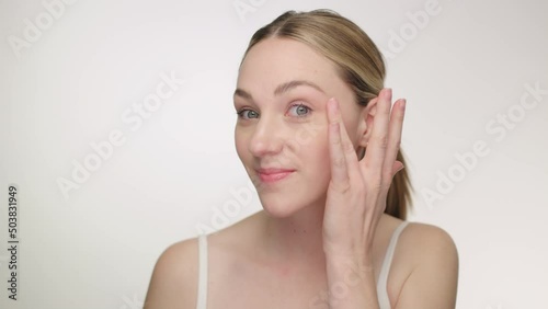 Beautiful young woman dabs anti aging cream lotion to neck and face