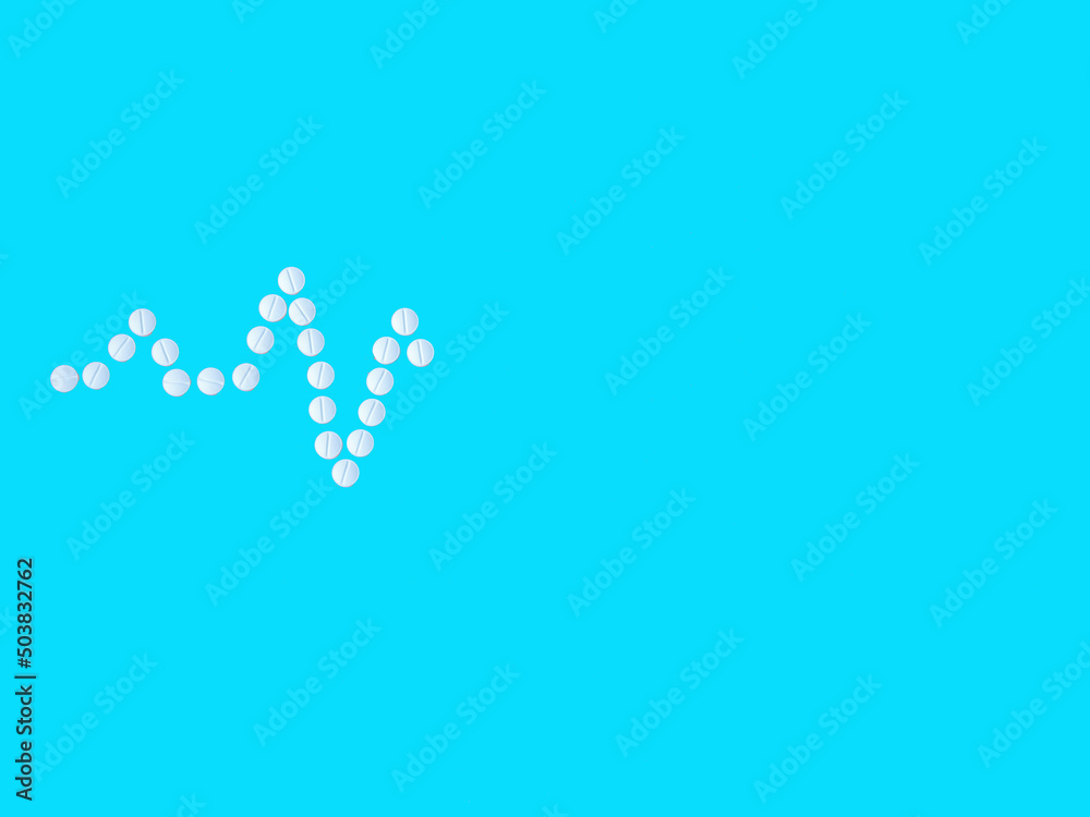 Heart shape and cardiogram made by medical pill on blue background. Healthcare, cardiology and medical concept. Top view flat lay, copy space Heart shape and cardiogram made by medical pill on blue background. Healthcare, cardiology and medical concept. Top view flat lay, copy space