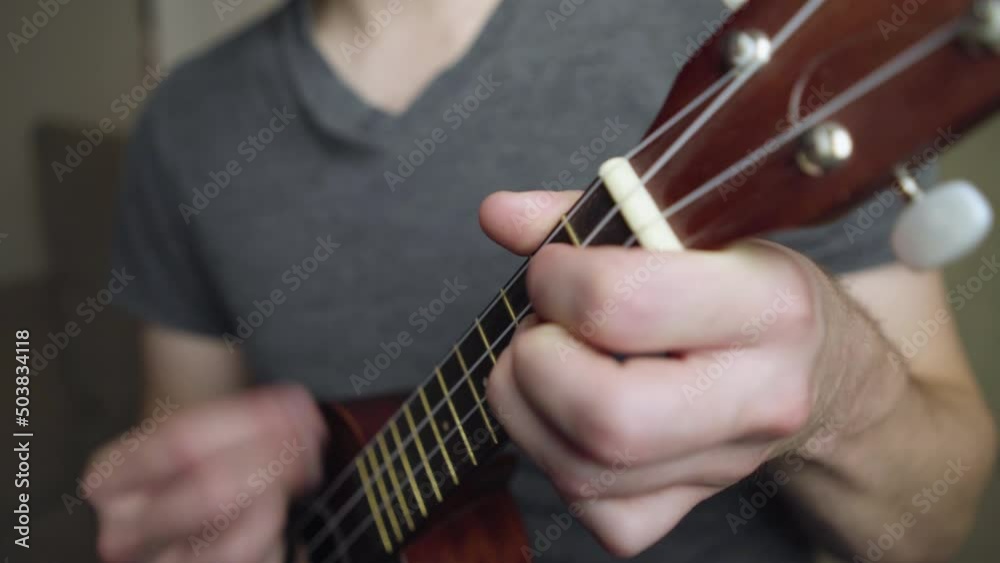 Close up of the neck and headstock as a pan strums a soprano ukulele. Close up of the neck and headstock as a pan strums a soprano ukulele.