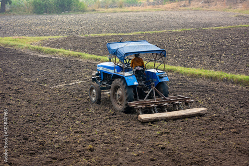 Indian farmer working with tractor in agriculture field