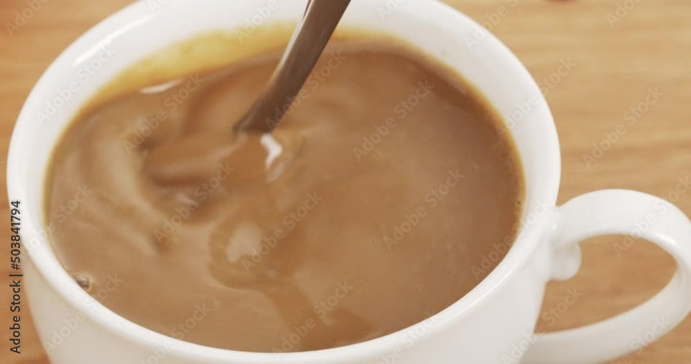 Using a spoon to stir the coffee in the cup. Using a spoon to stir the coffee in the cup.