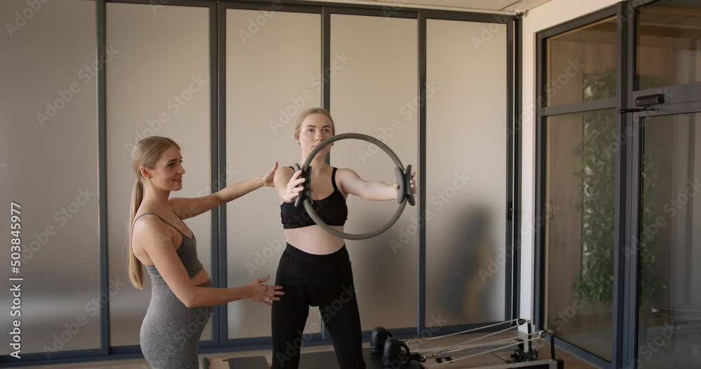 Pregnant woman doing Pilates exercises with instructor Pregnant woman doing Pilates exercises with instructor