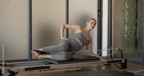 Pretty young pregnant model doing pilates on a machine photo