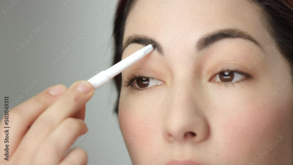Makeup tutorial: extreme closeup of eyebrow pencil being used by brunette model Makeup tutorial: extreme closeup of eyebrow pencil being used by brunette model